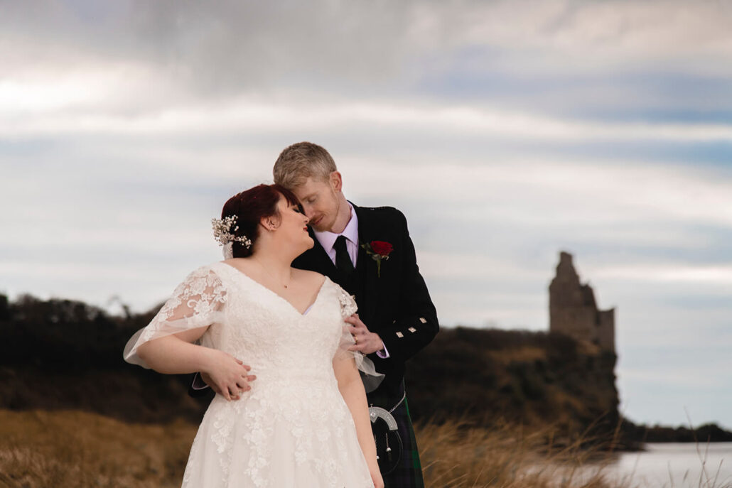 Bride and groom holding each other and touching heads with view of Greenan Castle in the background by Ayrshire wedding photographer Richard Campbell